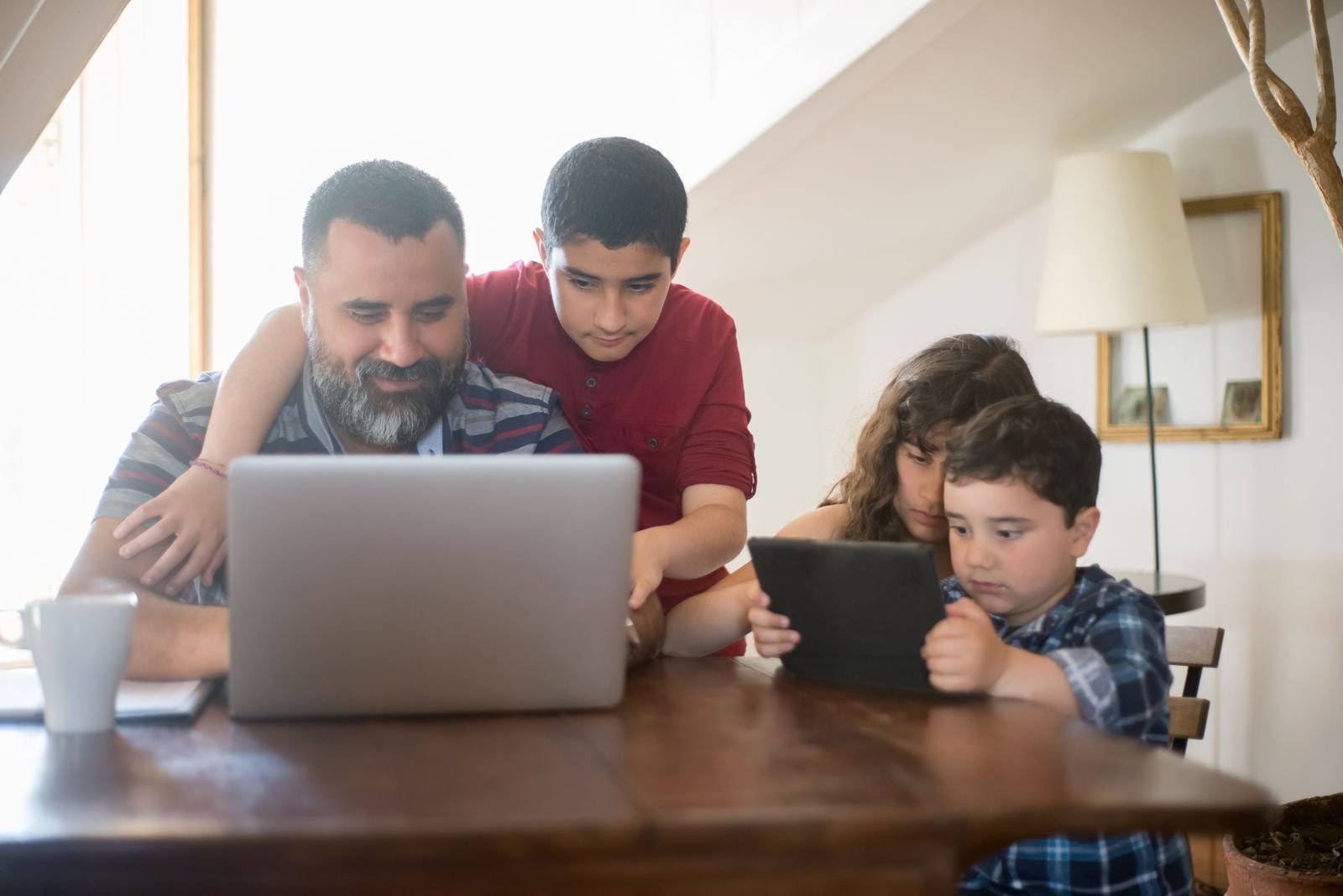 A father and his children learning together at a laptop at home