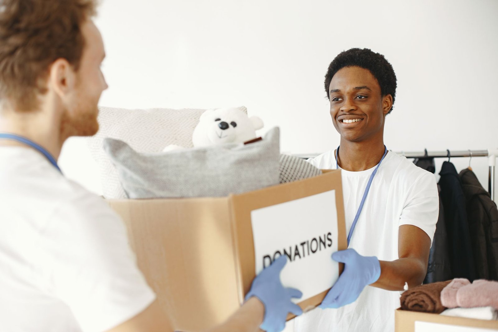 Three smiling students looking together at a laptop in a library, one holding a yellow book