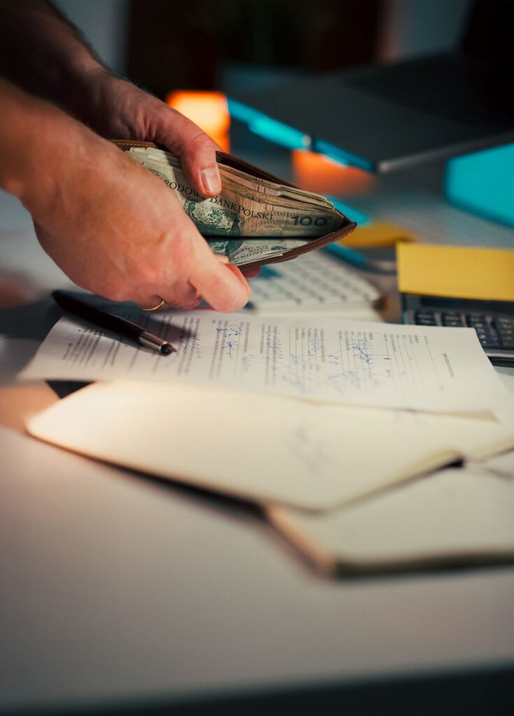 Hands counting money over documents, illustrating an investment scam