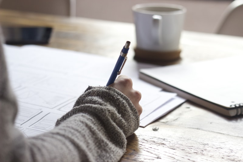 A designer sketching wireframes at a wooden desk