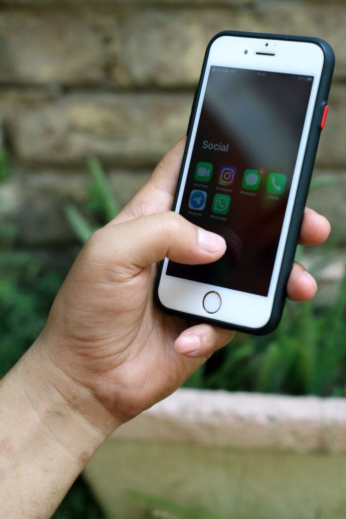 A person holding a smartphone showing social media apps