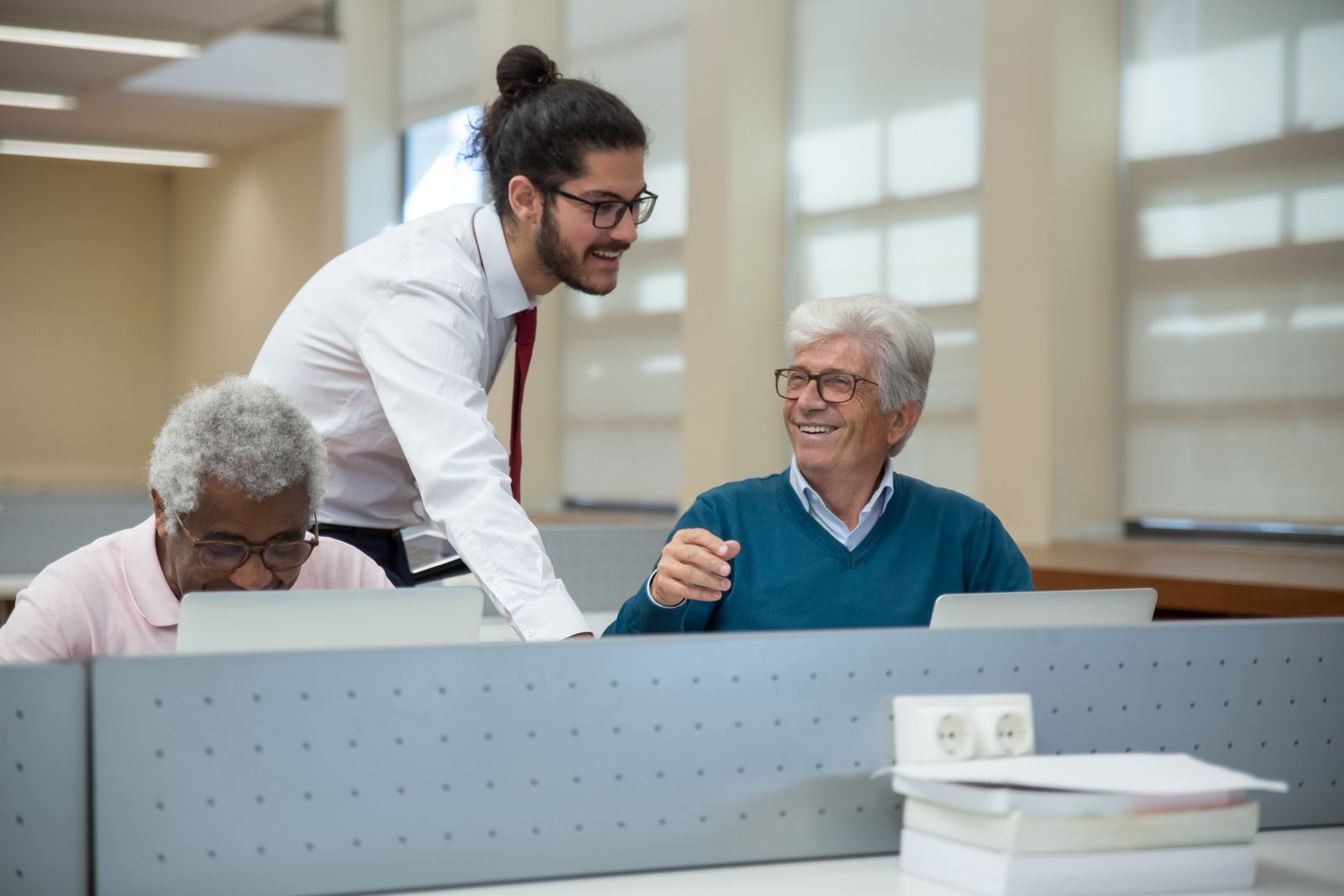 An instructor teaching a room of older adults to use laptops