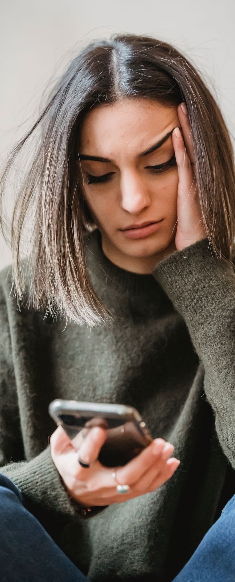 A concerned woman browsing her smartphone in a room