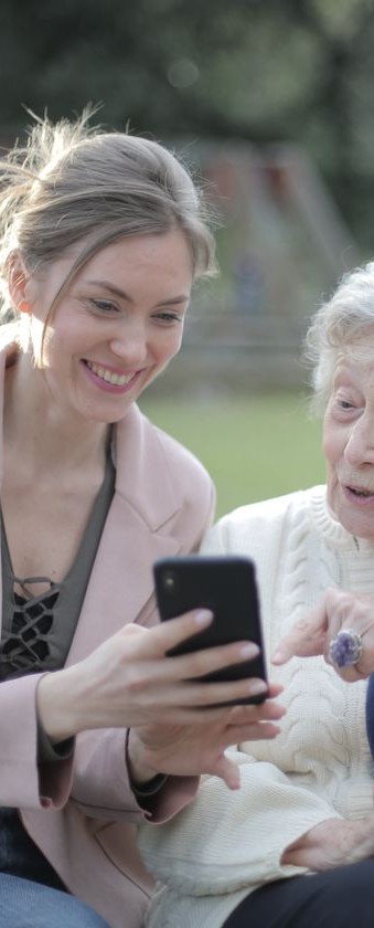 A senior mother and her adult daughter looking at a smartphone together