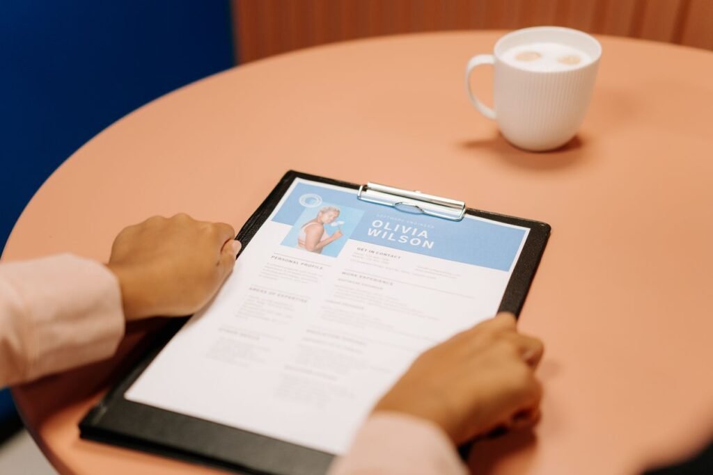 Hands holding a resume on a clipboard at a coffee table