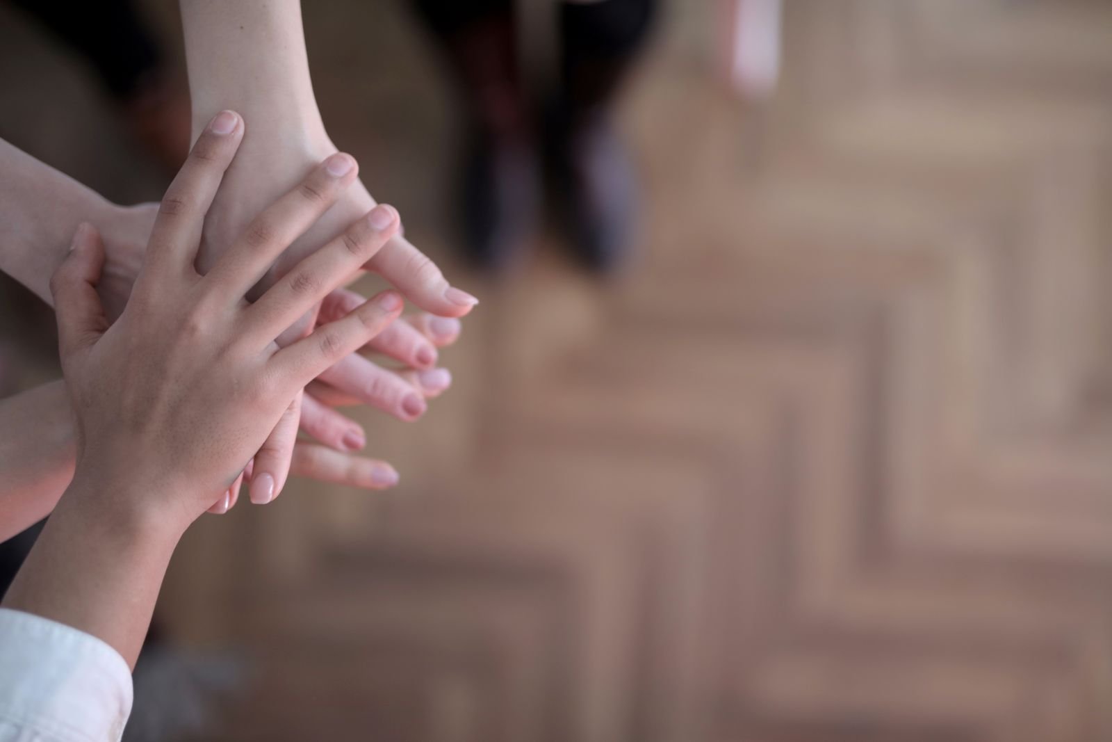 Close-up of several people stacking their hands together in a team huddle