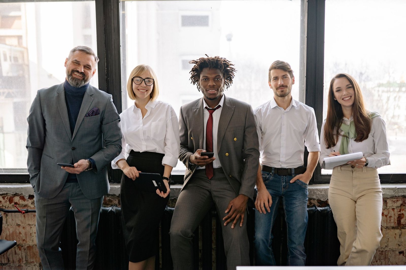 A group of people of different ages and backgrounds standing together with phones and tablets