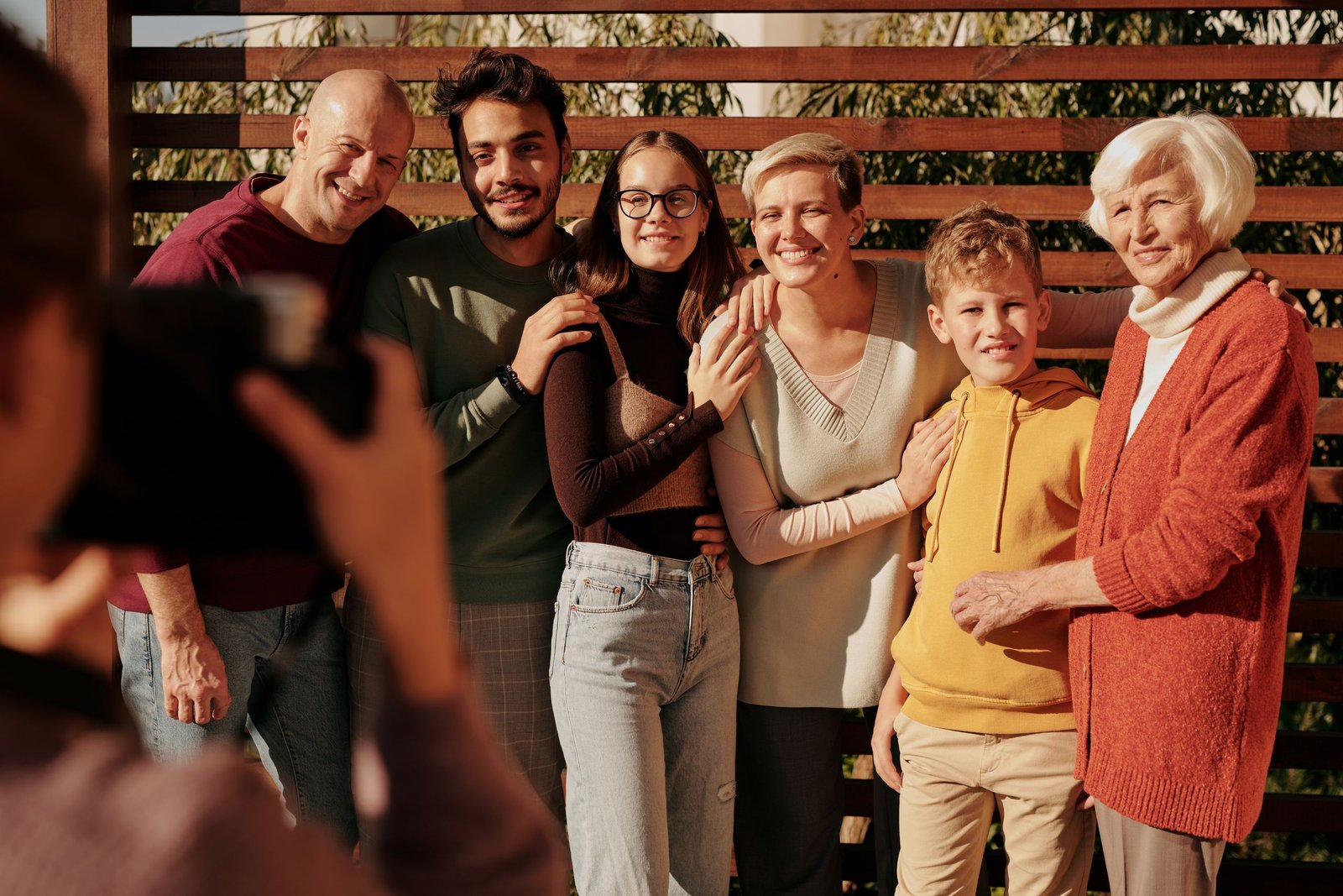 A group of people of different ages, from a young boy to an older woman, standing together
