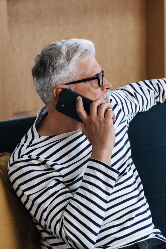 An older man looking concerned while talking on the phone